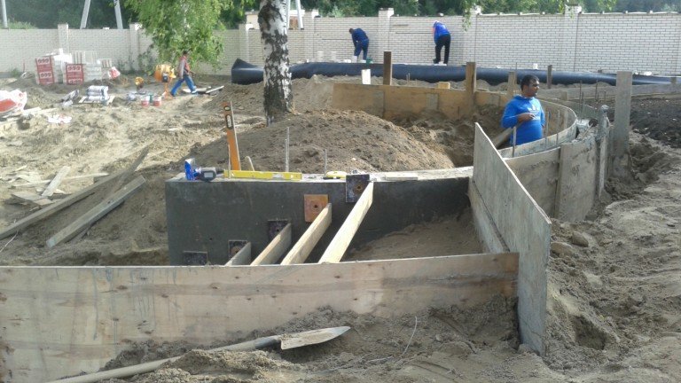 Подпорная стенка залита, устройство лестницы в процессе, идут работы на бассейне.
